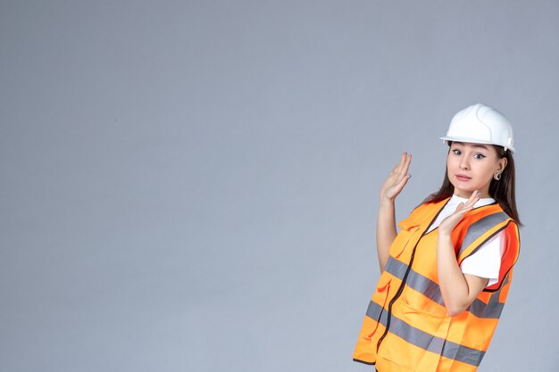 Vooraanzicht van vrouwelijke bouwer in uniform op witte muur