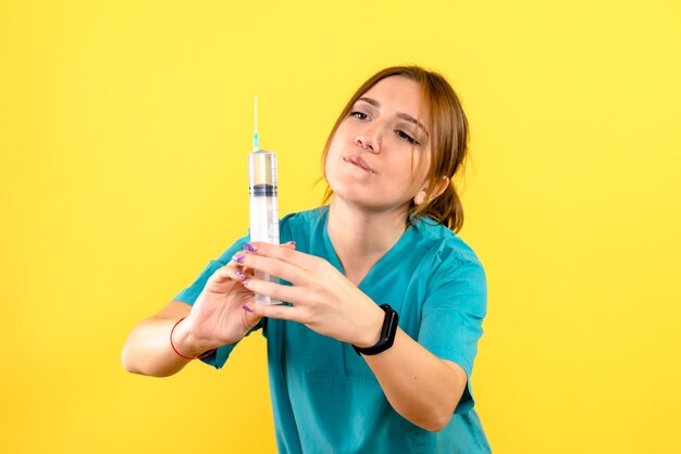Vooraanzicht van vrouwelijke dierenarts met injectie op gele muur