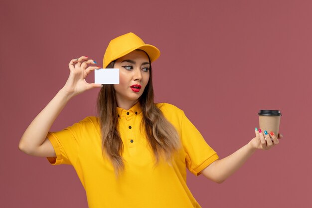 Gratis foto vooraanzicht van vrouwelijke koerier in geel uniform en pet met koffiekopje en witte kaart