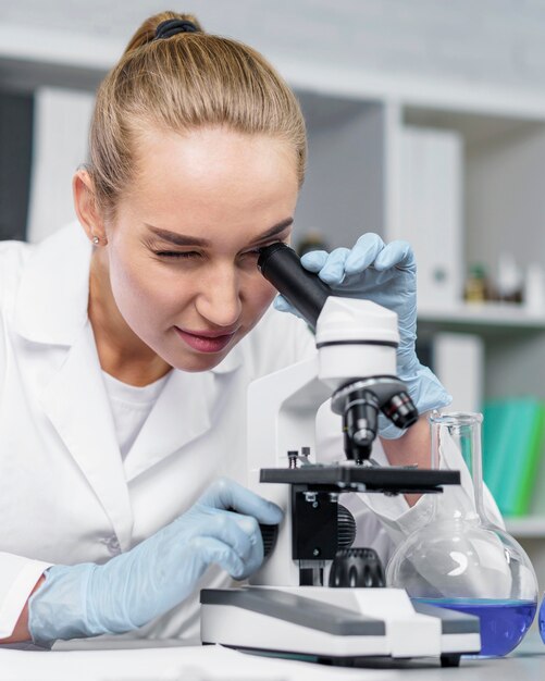 Vooraanzicht van vrouwelijke onderzoeker in het laboratorium met microscoop