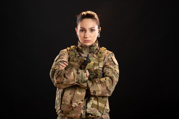 Vooraanzicht van vrouwelijke soldaat in camouflage op de zwarte muur
