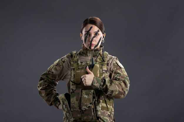 Vooraanzicht van vrouwelijke soldaat in militair uniform op donkere muur