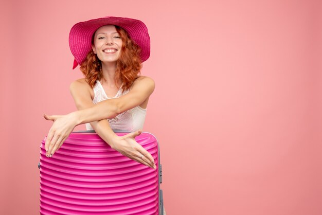 Vooraanzicht van vrouwelijke toerist met roze zak op de roze muur