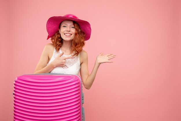 Vooraanzicht van vrouwelijke toerist met roze zak op de roze muur