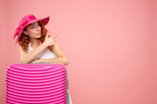 Gratis foto vooraanzicht van vrouwelijke toerist met roze zak op de roze muur