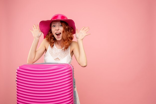 Gratis foto vooraanzicht van vrouwelijke toerist met roze zak op de roze muur