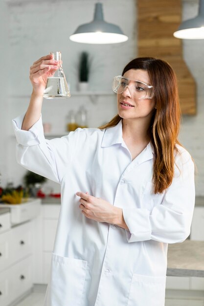 Vooraanzicht van vrouwelijke wetenschapper die met veiligheidsbril reageerbuis in het laboratorium houdt