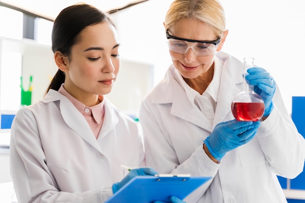 Vooraanzicht van vrouwelijke wetenschappers met chirurgische handschoenen in het laboratorium