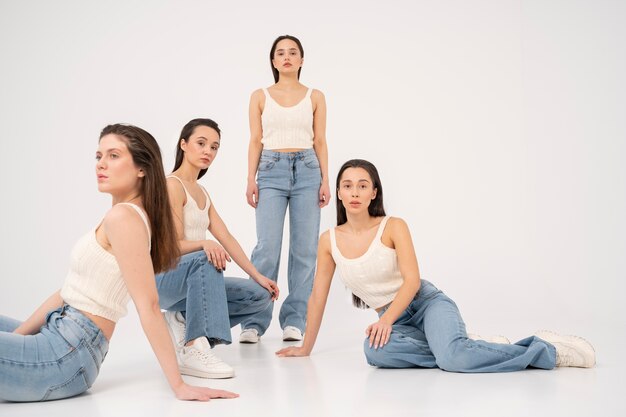 Vooraanzicht van vrouwen in tanktops en jeans poseren in minimalistische portretten