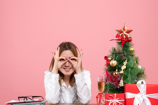 Vooraanzicht van werkneemster achter haar tafel met cadeautjes op roze