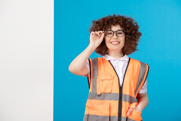 Vooraanzicht van werkneemster in uniform op de blauwe muur