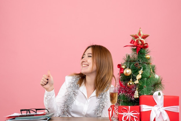 Vooraanzicht van werkneemster zittend achter haar tafel lachend op roze