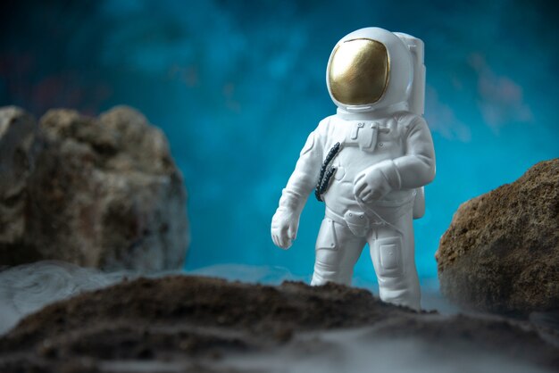 Gratis foto vooraanzicht van witte astronaut met rotsen op maan blauw bureau dood sci fi begrafenis