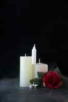 Gratis foto vooraanzicht van witte kaarsen met rode roos als herinnering op donkere muur