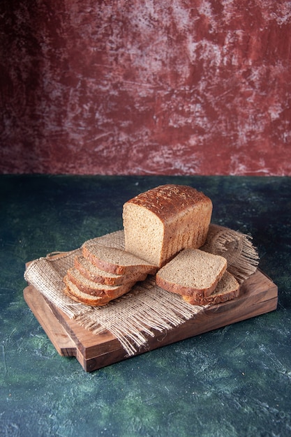 Vooraanzicht van zwarte sneetjes brood op naakte kleur handdoek op snijplanken op gemengde kleuren achtergrond