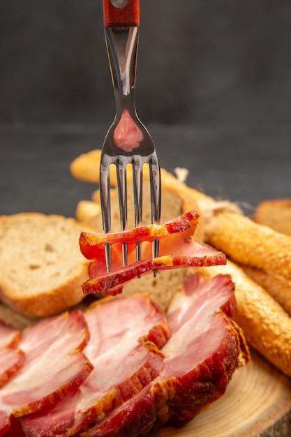 Gratis foto vooraanzicht vers gesneden ham met sneetjes brood en broodjes op een donkere kleur snackmaaltijd voedsel vleesvarken