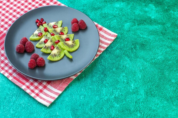 Vooraanzicht vers gesneden kiwi's met frambozen op groene oppervlaktebessen exotisch fruit foto tropische kleur