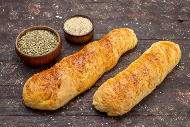 Vooraanzicht vers lekker gebak broodje gevormd gebakje met kruiden op bruin houten bureau