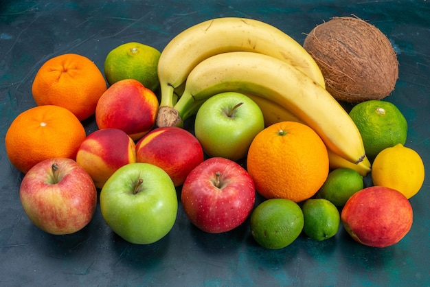 Gratis foto vooraanzicht verschillende fruitsamenstelling bananen mandarijnen appels op donkerblauw bureau fruit verse zachte rijpe kleur vitamine