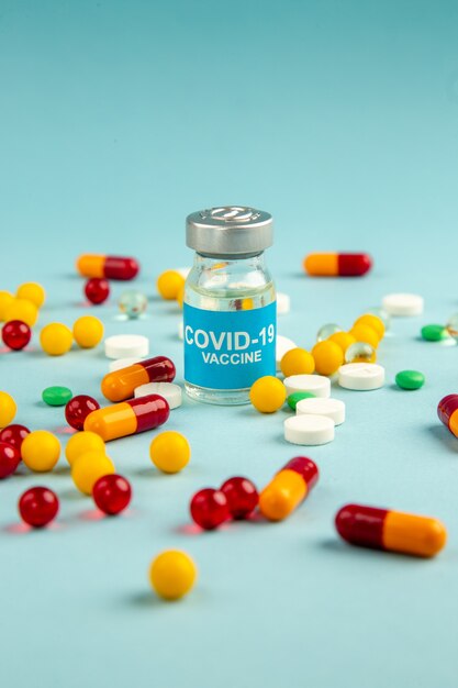 vooraanzicht verschillende kleurrijke pillen met vaccin op blauwe ondergrond lab gezondheid covid ziekenhuis virus wetenschap pandemie drug kleuren
