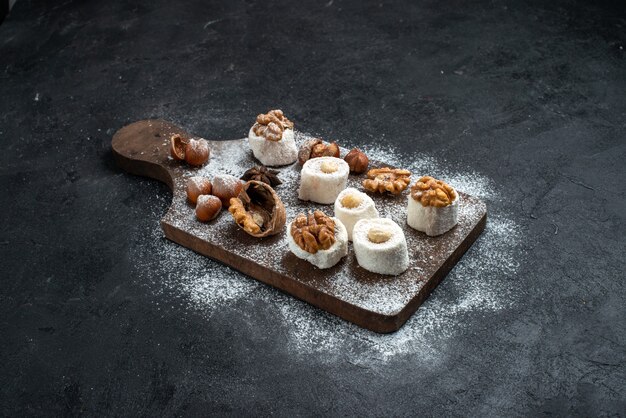 Vooraanzicht verschillende koekjes met cakes en walnoten op het donkergrijze oppervlak cake biscuit suiker bak zoet koekje