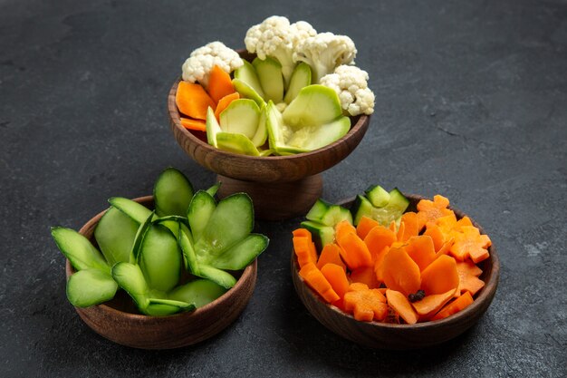 Gratis foto vooraanzicht verschillende ontworpen groenten in potten op grijze ruimte