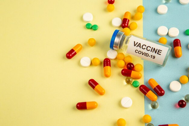 vooraanzicht verschillende pillen met vaccin op geel-blauwe achtergrond pandemie ziekenhuis covid wetenschap virus lab drug gezondheid kleur