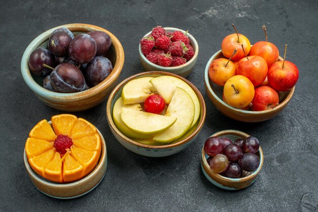 Vooraanzicht verschillende soorten fruit samenstelling vers en gesneden fruit op donkere achtergrond vers rijp fruit zachte gezondheid