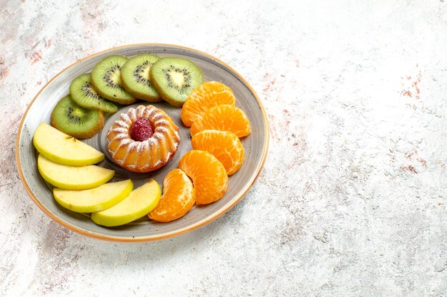 Vooraanzicht verschillende vruchten samenstelling vers en gesneden fruit met kleine cake op witte achtergrond zacht rijp fruit gezondheid