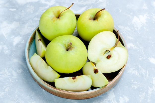 Vooraanzicht verse groene appels gesneden en hele vruchten op lichte oppervlakte fruit verse, zachte rijp voedsel vitamine