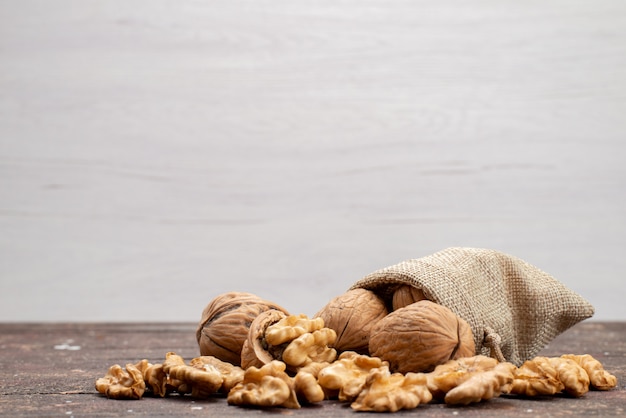 Vooraanzicht verse hele walnoten in schelpen en opgeruimd op grijze, noten walnoot snack