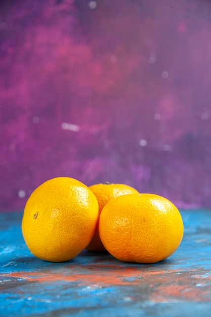 Gratis foto vooraanzicht verse mandarijnen op blauw-paarse tafel