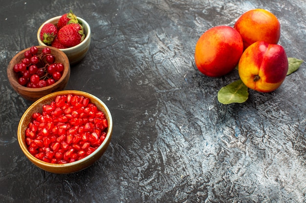 Gratis foto vooraanzicht verse perziken met rood fruit op licht-donkere tafel fruitboomtuin