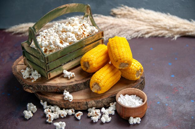 Vooraanzicht verse popcorn met gele likdoorns op het donkere oppervlak snack popcorn maïsvoedsel