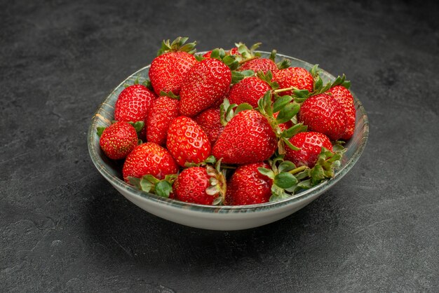 Vooraanzicht verse rode aardbeien in plaat op grijze achtergrond boomsap kleur wilde smaak bessen zomer