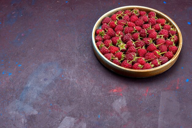 Vooraanzicht verse rode frambozen rijpe en zure bessen op de donkerblauwe achtergrond bessen fruit zachte zomer voedsel vitamine