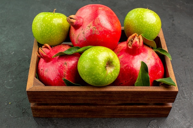 Gratis foto vooraanzicht verse rode granaatappels met groene appels op de donkere kleur van het oppervlak rijp fruit