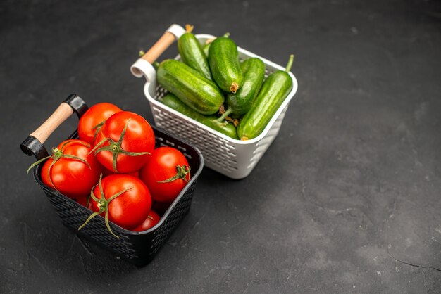 Vooraanzicht verse rode tomaten met komkommers in manden op donkere achtergrond rijpe maaltijdsalade kleurenfoto