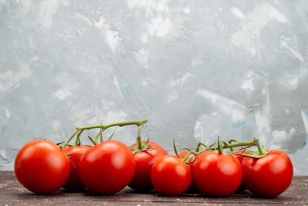 Vooraanzicht verse rode tomaten rijp en geheel op hout, bruine plantaardige het voedselkleur van de fruitbes