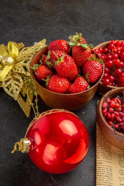 Vooraanzicht verse rode veenbessen met ander fruit rond kerstspeelgoed op een donkere achtergrond fruitkleur kerstvakantie berry