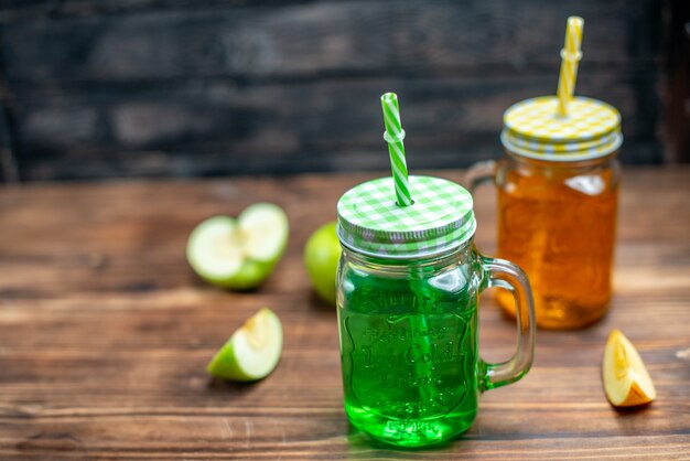 Vooraanzicht verse sappen in glazen blikjes met fruit op donkere kleur drankje cocktailfruit