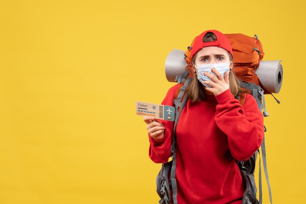 Gratis foto vooraanzicht verwarde vrouwelijke reiziger met rugzak en masker met vliegtuigticket