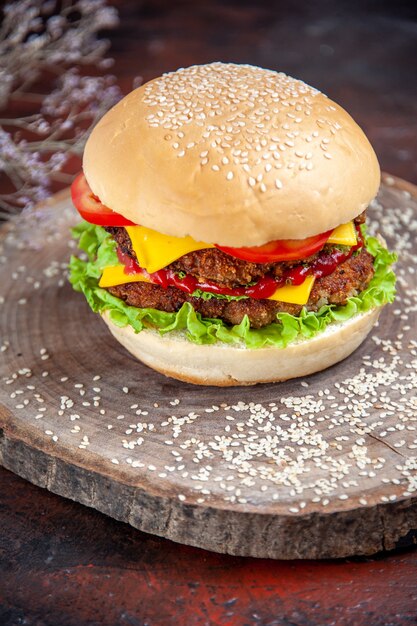 Vooraanzicht vlees hamburger met kaassalade en tomaten op de donkere achtergrond