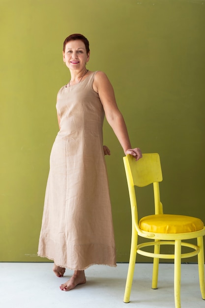 Gratis foto vooraanzicht volwassen vrouw met gele stoel