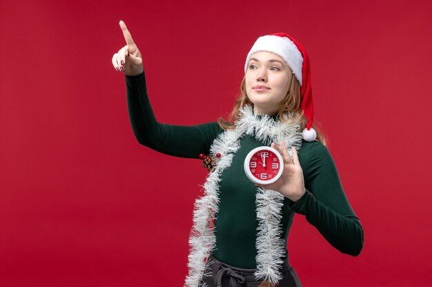 Gratis foto vooraanzicht vrij vrouwelijke bedrijf klok op de rode achtergrond