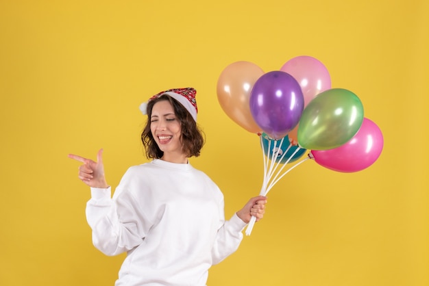 Vooraanzicht vrij wijfje dat kleurrijke ballons op geel houdt