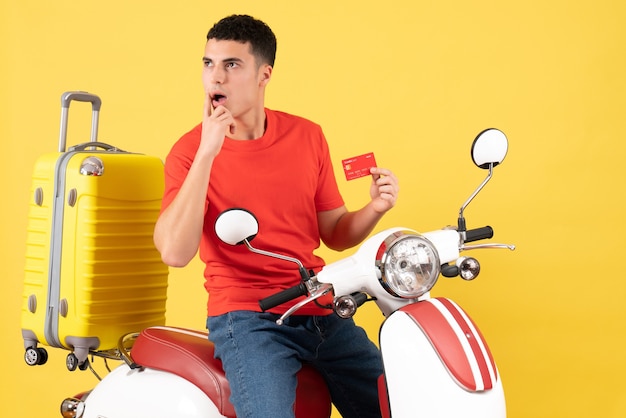 Gratis foto vooraanzicht vroeg zich af jonge man in rood t-shirt op bromfiets met creditcard