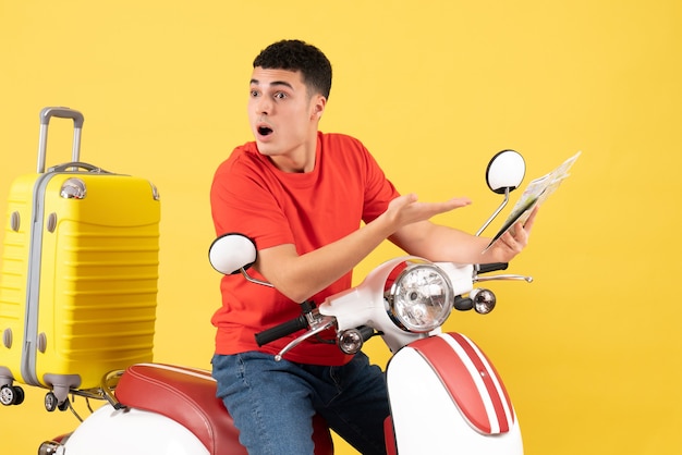 Vooraanzicht vroeg zich af jonge man in rood t-shirt op bromfiets met kaart