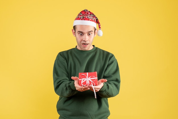 Vooraanzicht vroeg zich jonge man af die naar zijn geschenk op geel keek