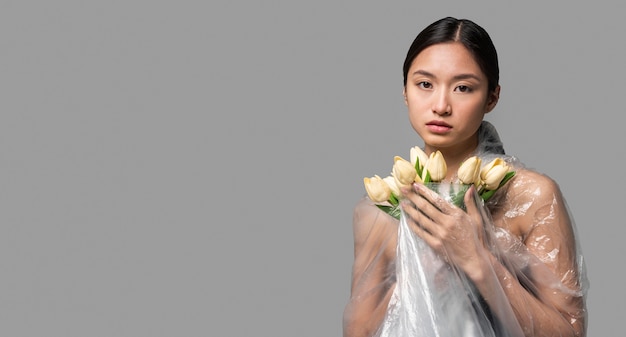 Vooraanzicht vrouw bedekt met plastic met een boeket bloemen